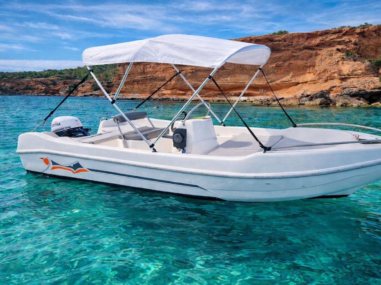 Indalboats Voraz 450 blanca con toldo bimini fondeada frente a un acantilado rojizo