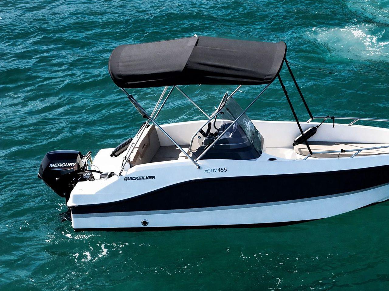 Quicksilver Activ 455 Open blanca y negra con toldo bimini negro sobre agua esmeralda