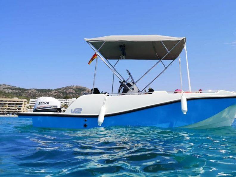 Barco sin licencia V2 Boat 5.0 Sport azul y blanco con toldo bimini fondeado en aguas turquesas